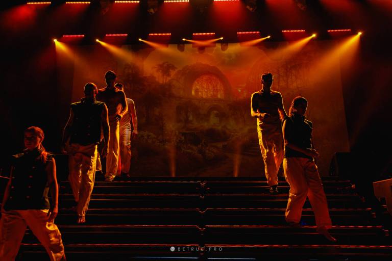 Performers silhouetted in amber light